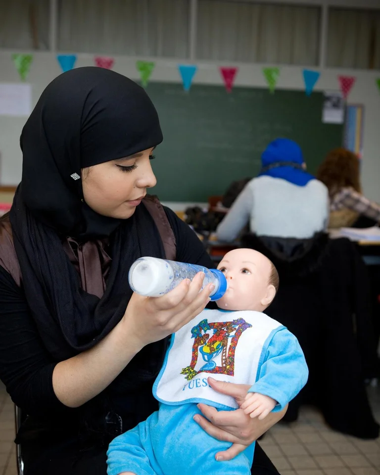 Studente van CLW Antwerpen oefent in de klas het verzorgen van een baby met een voedingspop