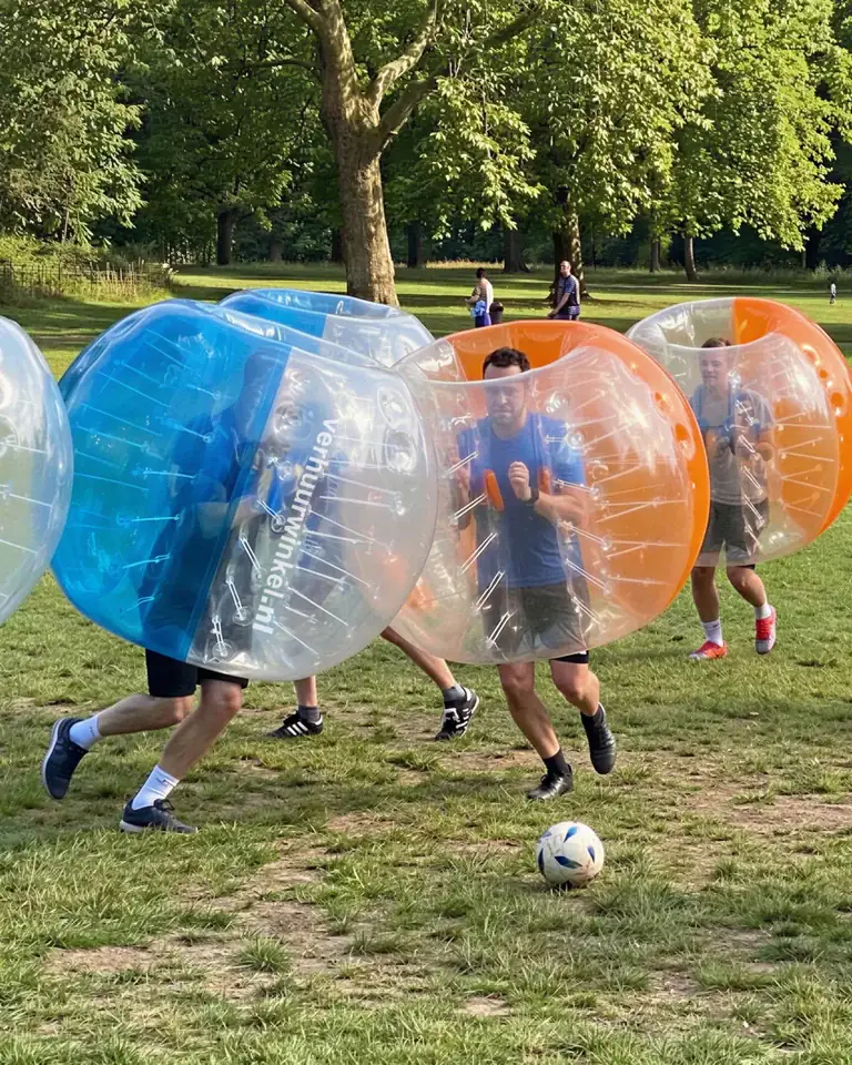 Spelers in transparante bubbelpakken rennen op elkaar af tijdens een potje bubbelvoetbal